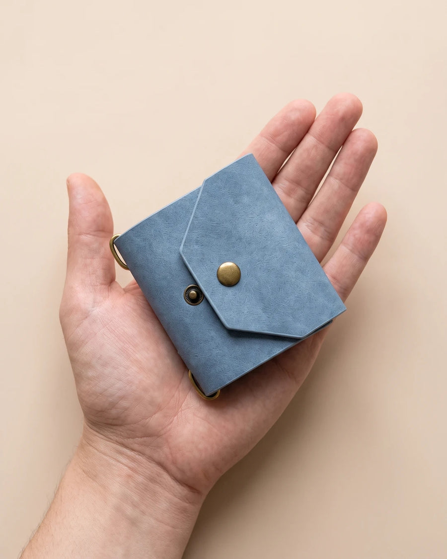 06-in-hand.webp: De dichtgevouwen wallet in een hand, ter grootte van een stapel speelkaarten