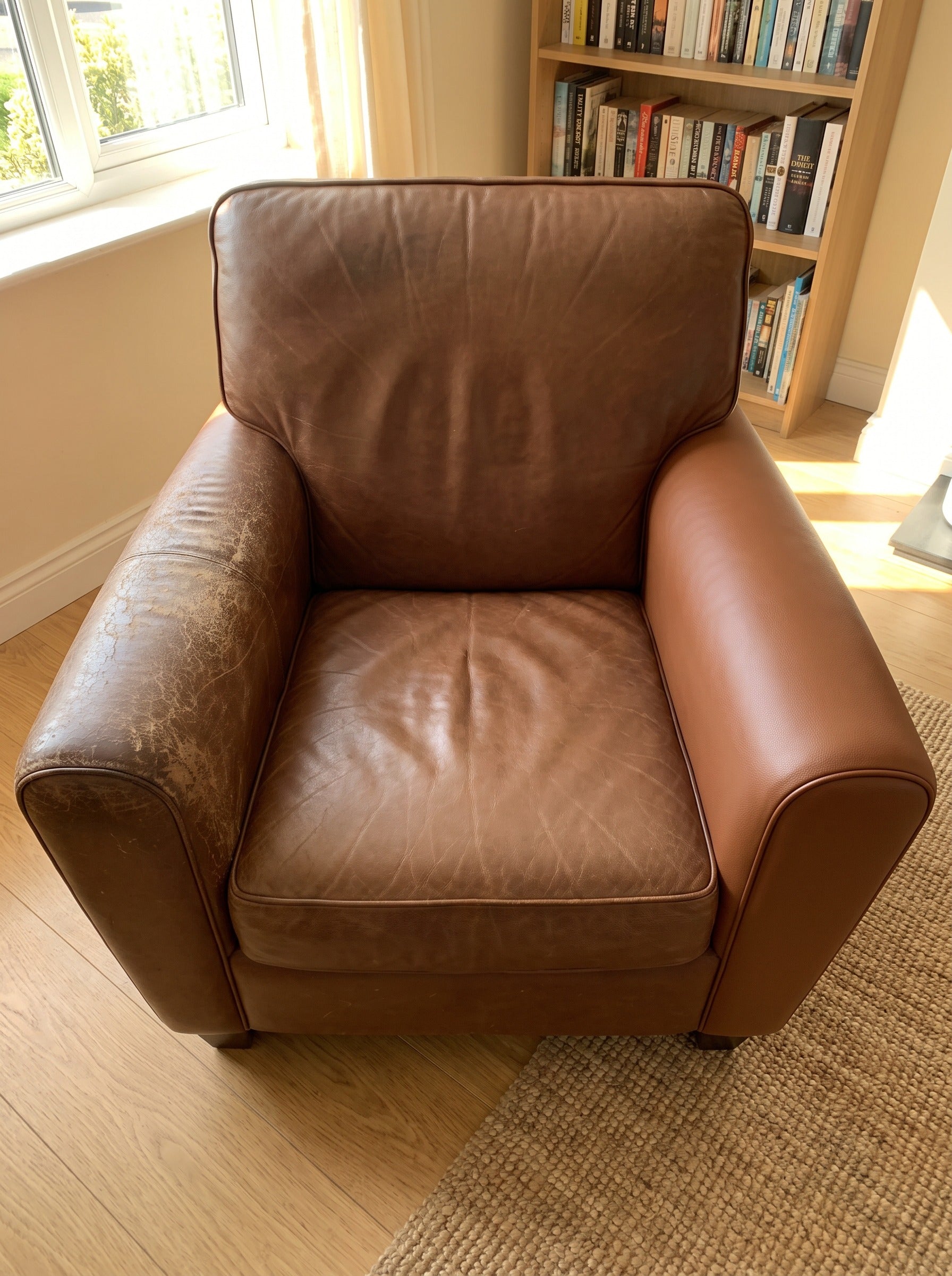 Leren fauteuil met links een versleten armleuning en rechts een opnieuw beklede